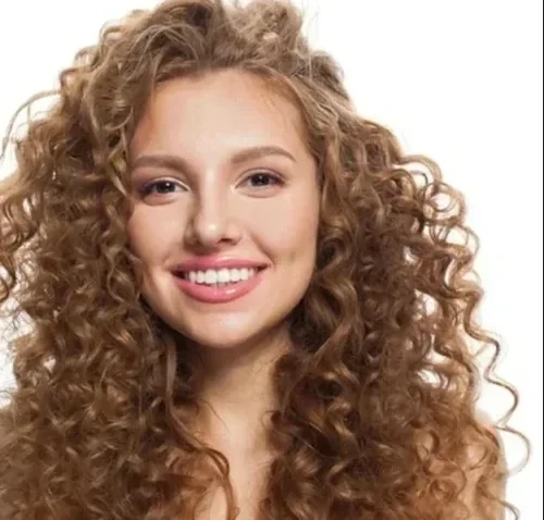 Mèche de cheveux bouclés humides traversée par la brosse ajourée, les boucles regroupées en spirales nettes