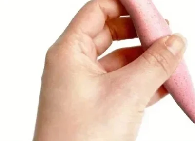 Mains remontant une mèche de cheveux bouclés humides en accordéon vers le cuir chevelu, geste du scrunch